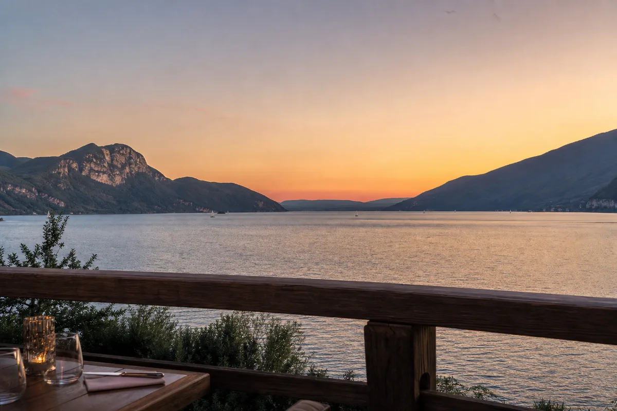 Vue panoramique du lac du Bourget au coucher du soleil depuis une terrasse de restaurant